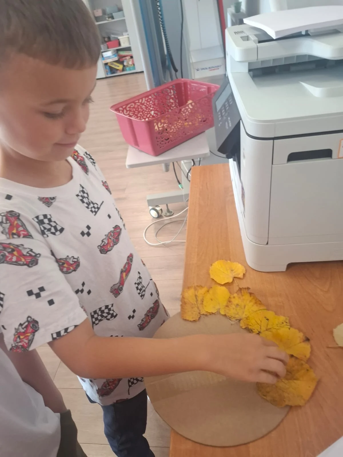 Dzieci ze świetlicy „LIPA” zbierają jesienne liście i szyszki, a następnie wspólnie tworzą z nich słonecznik. Zdjęcia przedstawiają zbieranie materiałów, układanie liści i szyszek oraz gotową pracę z łodygą z patyka i dekoracją z mniejszych kwiatów.