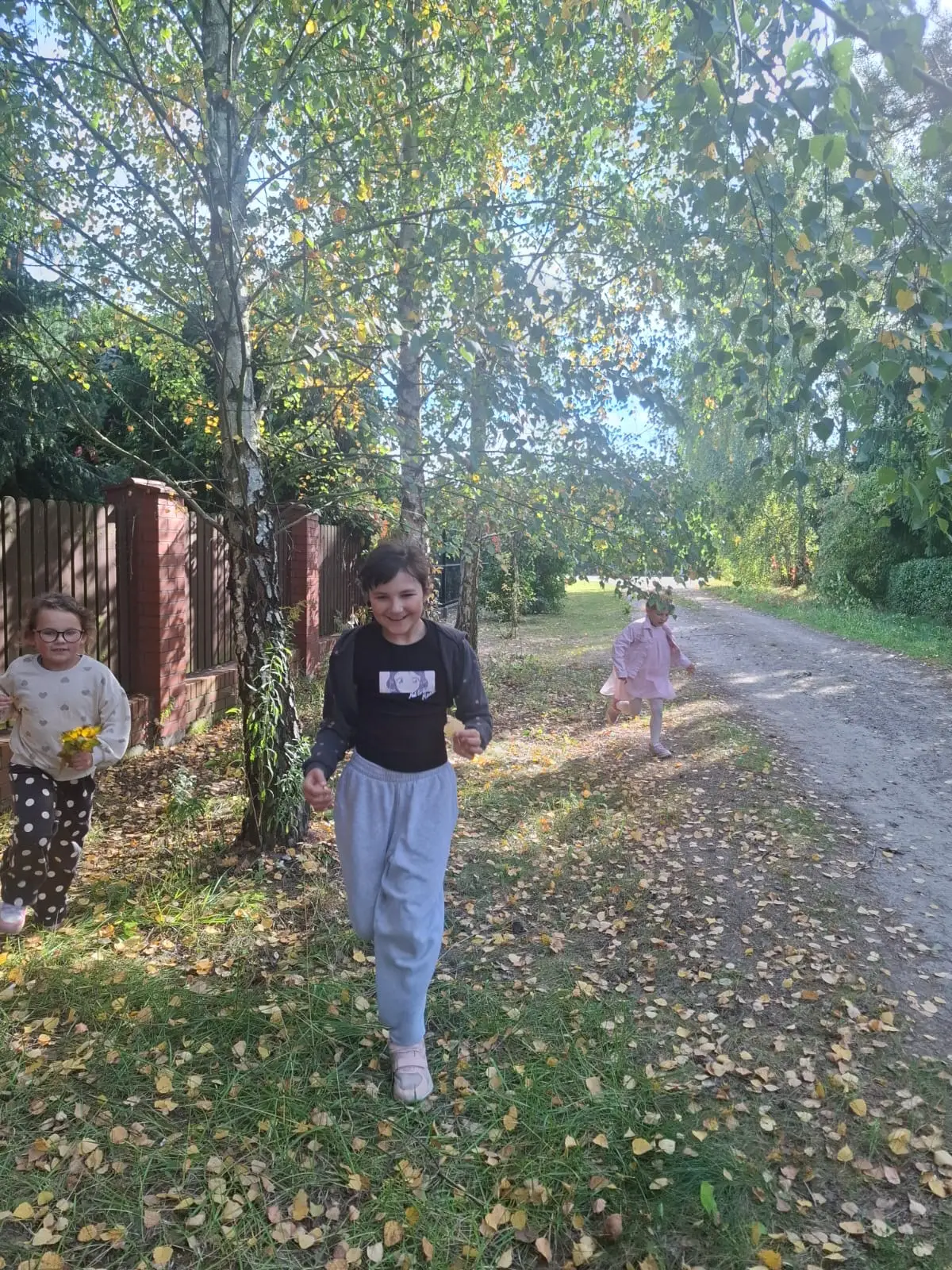 Dzieci ze świetlicy „LIPA” zbierają jesienne liście i szyszki, a następnie wspólnie tworzą z nich słonecznik. Zdjęcia przedstawiają zbieranie materiałów, układanie liści i szyszek oraz gotową pracę z łodygą z patyka i dekoracją z mniejszych kwiatów.