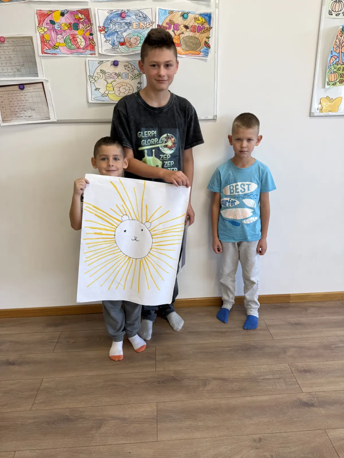 Zdjęcia z Dnia Makaronu w świetlicy. Dzieci pracują w grupach nad kolorowymi plakatami przedstawiającymi makarony i przygotowane z nich dania oraz prezentują gotowe prace.