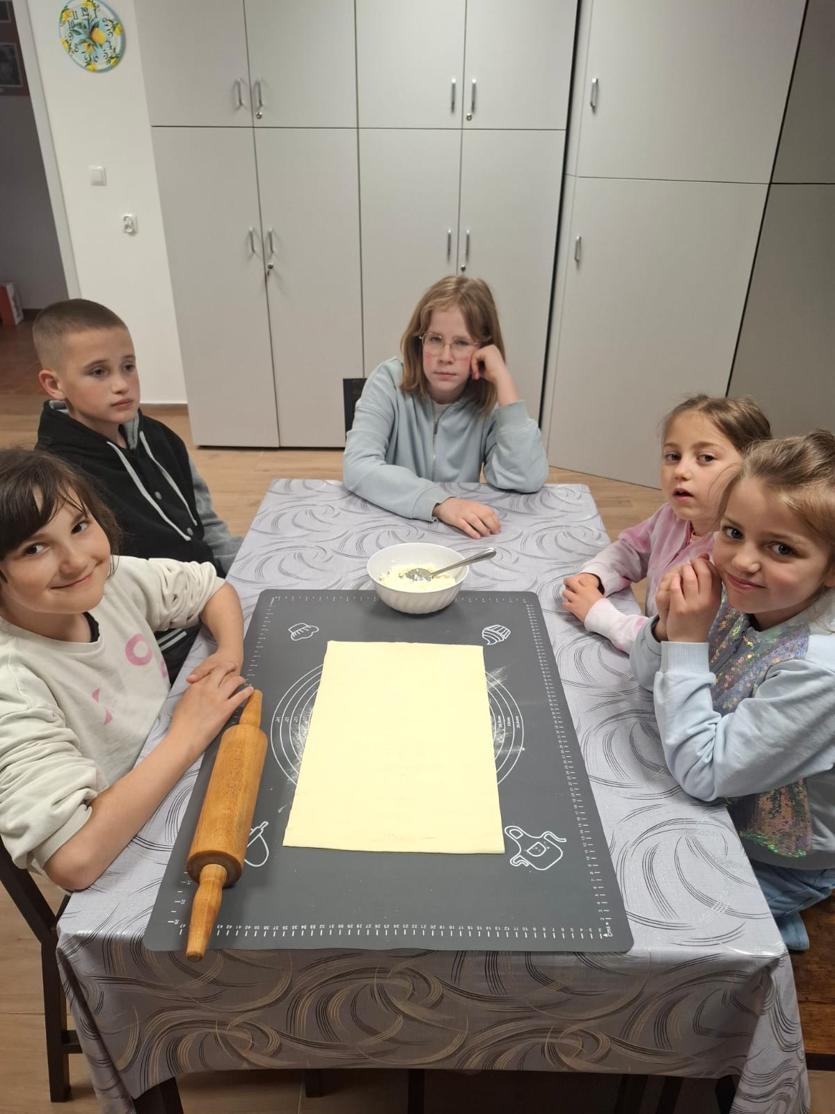 Dzieci przygotowują francuskie kieszonki na słodko podczas zajęć kulinarnych w świetlicy.