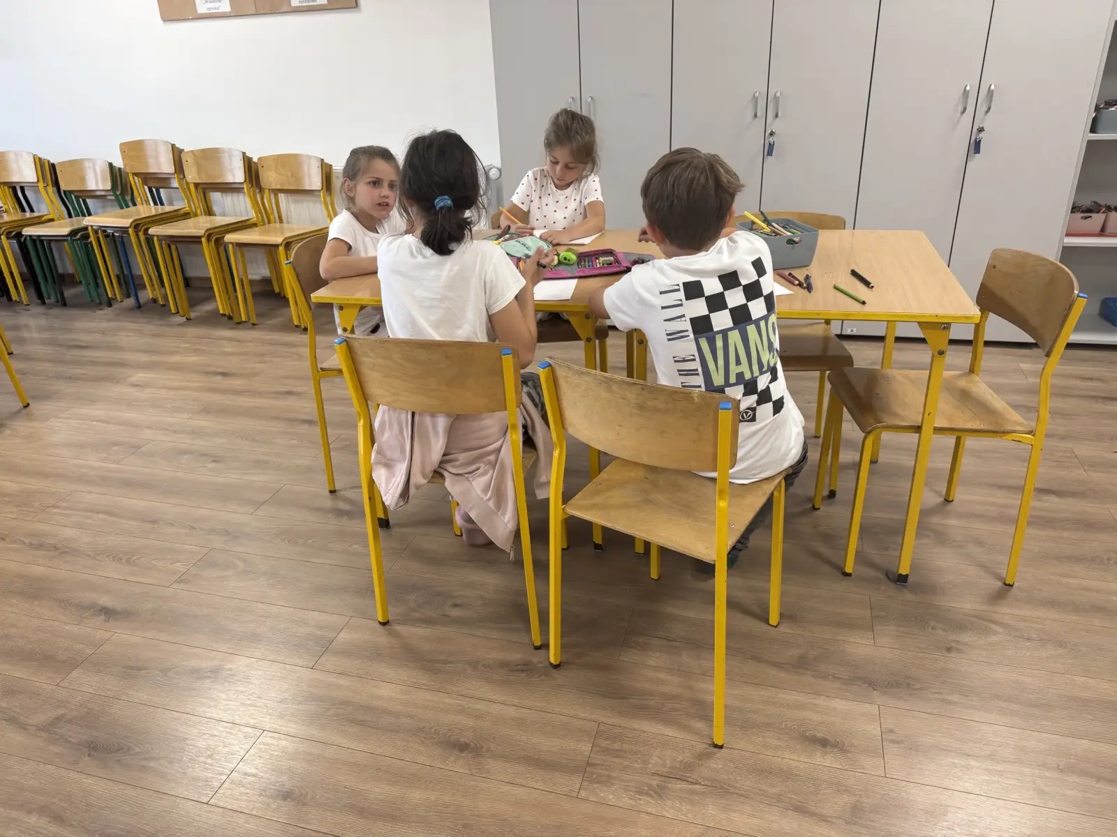 Dzieci podczas zajęć świetlicowych wykonują prace plastyczne przedstawiające swoich przyjaciół.